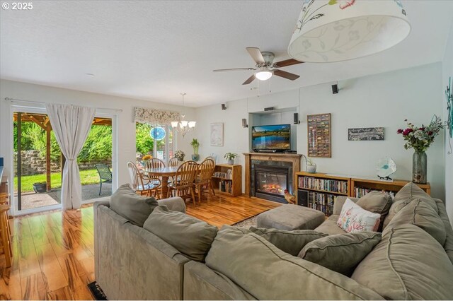 287 SW Oliver Ct, Dundee, OR 97115 - living room featuring light wood-style floors, ceiling fan, a chandelier, and a glass covered fireplace