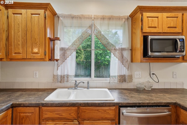 17701 Koch Ct, Sandy, OR 97055 - kitchen with stainless steel appliances, a sink, dark countertops, and brown cabinetry