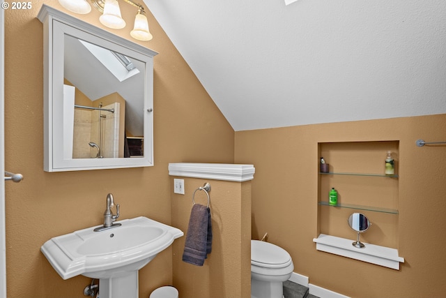 bathroom with a shower, sink, toilet, and lofted ceiling with skylight