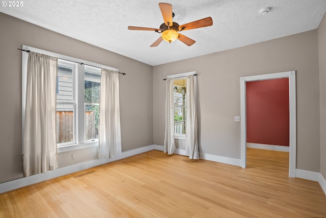 unfurnished room with ceiling fan, a textured ceiling, and light wood-type flooring