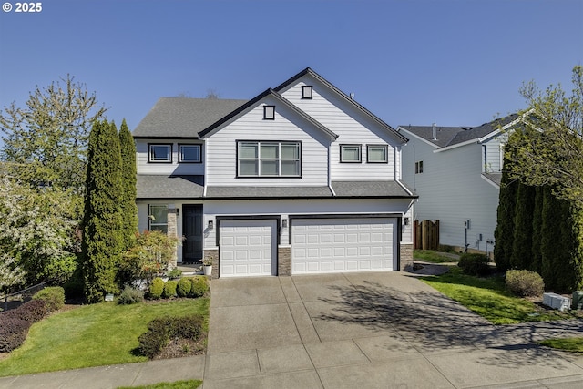 traditional-style home featuring a shingled roof, a front lawn, driveway, stone siding, and a garage
