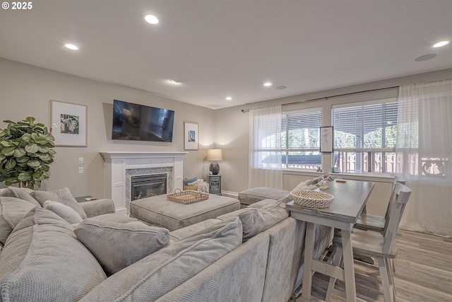 living room with light wood-style flooring, recessed lighting, and a high end fireplace