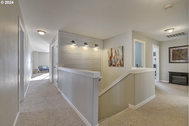 corridor with visible vents, baseboards, light carpet, and an upstairs landing