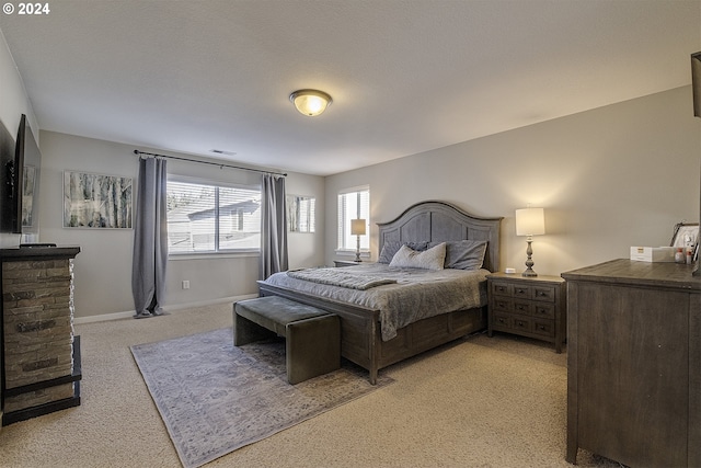 bedroom with baseboards, visible vents, and light colored carpet