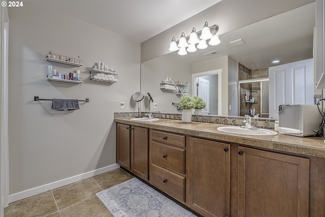 full bathroom with a shower stall, double vanity, visible vents, a sink, and baseboards