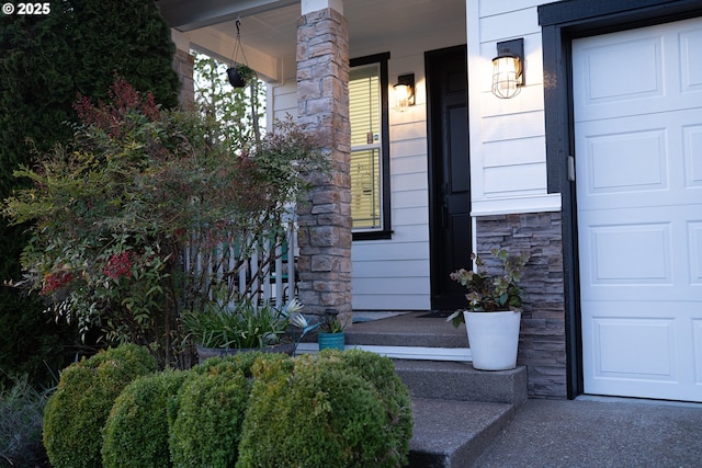 view of exterior entry with stone siding, covered porch, and a garage