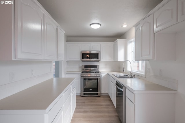 kitchen featuring white cabinetry, appliances with stainless steel finishes, sink, and light wood-type flooring