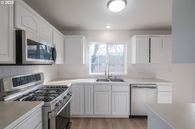 kitchen featuring stainless steel appliances, white cabinetry, sink, and light hardwood / wood-style floors