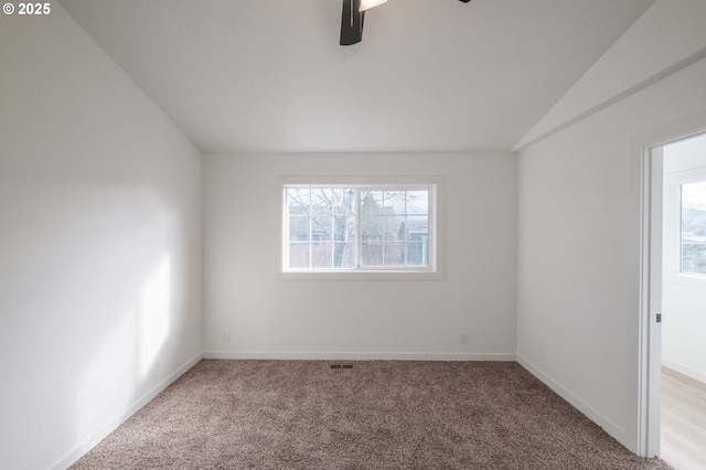 unfurnished room with lofted ceiling, plenty of natural light, and carpet