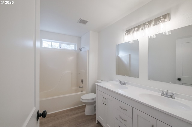 full bathroom featuring hardwood / wood-style flooring, washtub / shower combination, vanity, and toilet