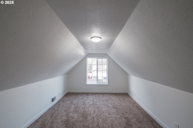 bonus room featuring lofted ceiling, a textured ceiling, and carpet flooring