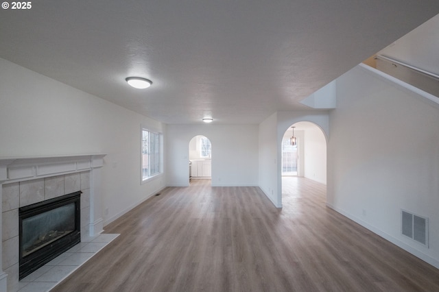 unfurnished living room featuring a tiled fireplace and light wood-type flooring