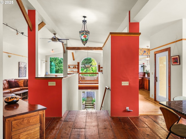 interior space featuring a ceiling fan, rail lighting, vaulted ceiling with beams, and hardwood / wood-style flooring