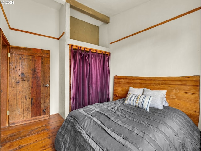 bedroom featuring lofted ceiling with beams and wood finished floors