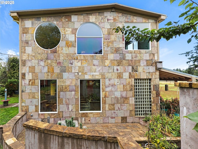 back of property featuring stone siding