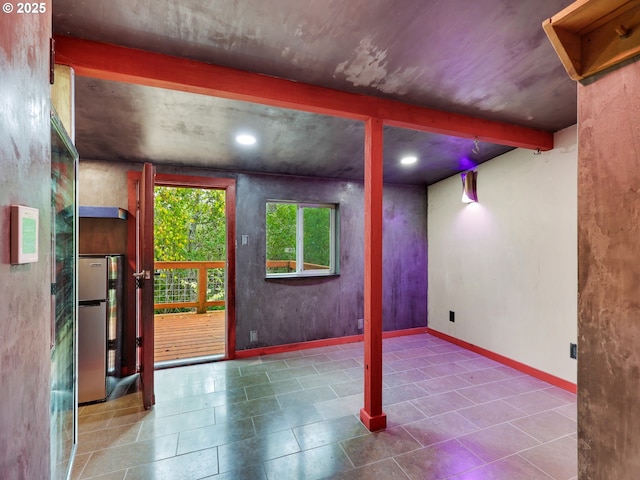 basement with baseboards, freestanding refrigerator, tile patterned flooring, and recessed lighting