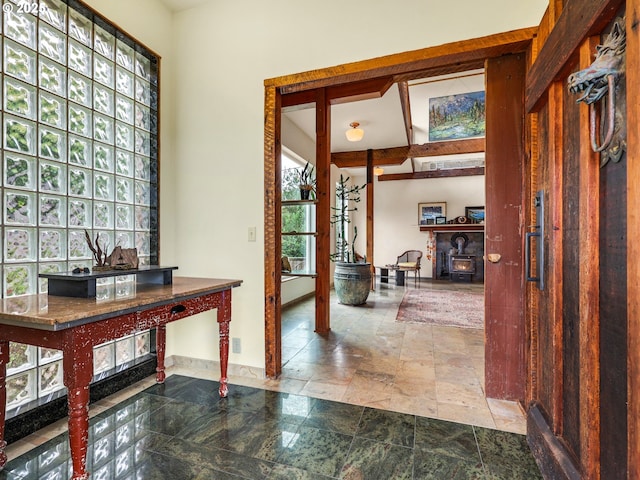 foyer featuring baseboards, a wood stove, and stone finish flooring