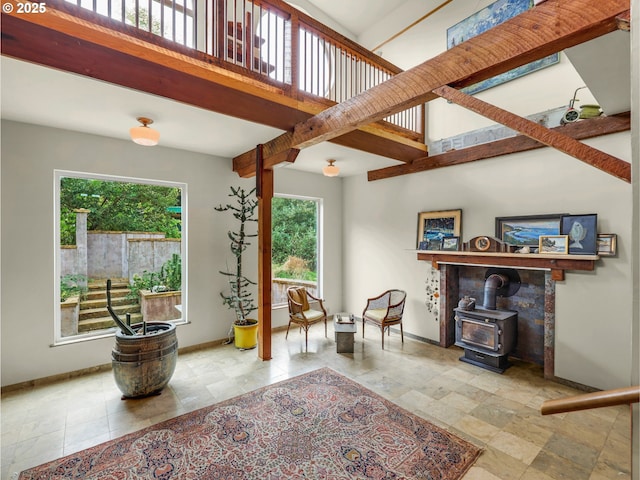 sitting room featuring a healthy amount of sunlight, baseboards, and a wood stove