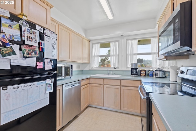 kitchen with appliances with stainless steel finishes, sink, and light brown cabinetry