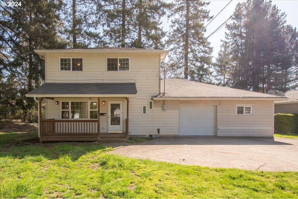 front facade with a porch, a front yard, and a garage