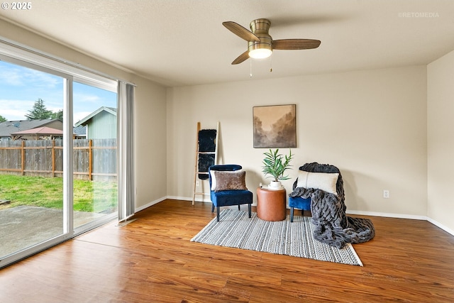 sitting room featuring wood finished floors, baseboards, and a ceiling fan