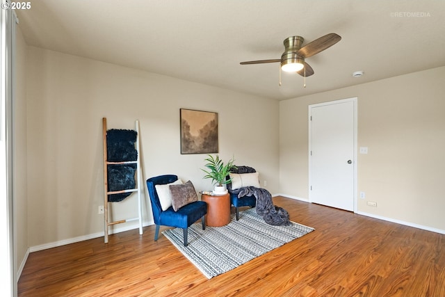 living area featuring wood finished floors, a ceiling fan, and baseboards