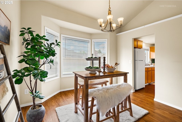 dining space featuring a chandelier, baseboards, dark wood-type flooring, and vaulted ceiling
