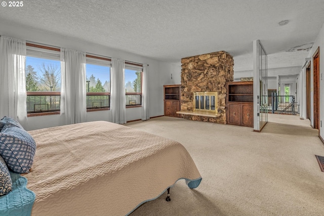 carpeted bedroom featuring a fireplace, visible vents, and a textured ceiling