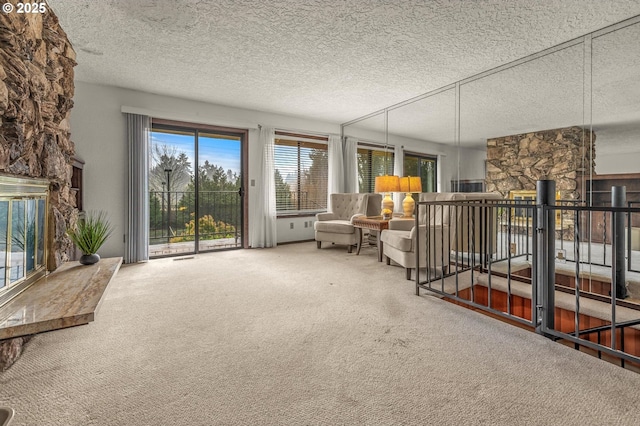 sitting room with carpet, a stone fireplace, and a textured ceiling