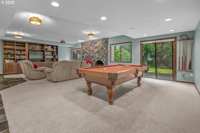 playroom with carpet, a stone fireplace, a textured ceiling, and recessed lighting