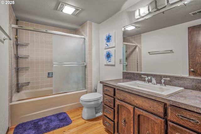 full bath featuring enclosed tub / shower combo, toilet, wood finished floors, vanity, and visible vents