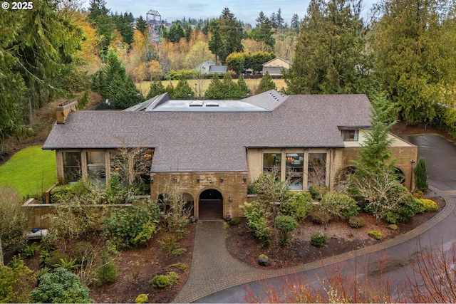 view of front facade featuring a shingled roof, decorative driveway, and brick siding