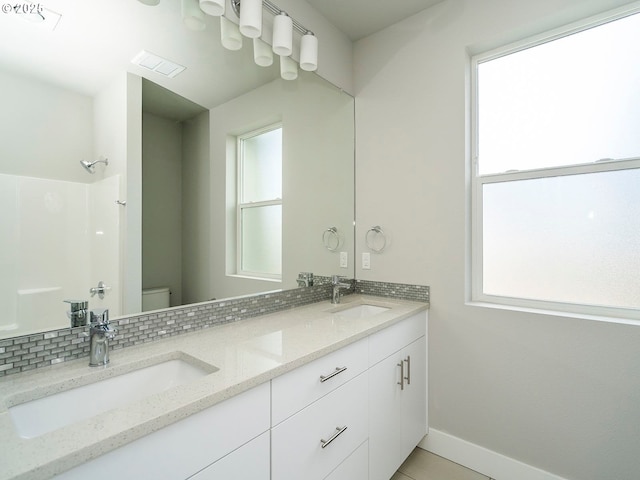 full bath with visible vents, a sink, toilet, and double vanity