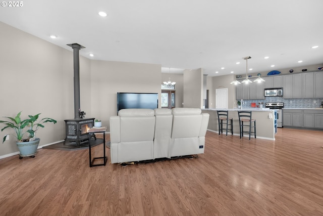 living area featuring baseboards, light wood finished floors, a wood stove, and recessed lighting