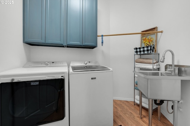 clothes washing area featuring a sink, cabinet space, light wood-style floors, and washer and dryer