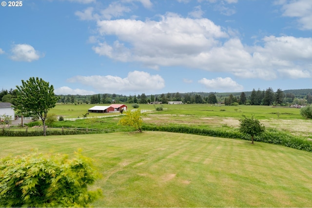 view of yard with fence, a pole building, an outdoor structure, and a rural view