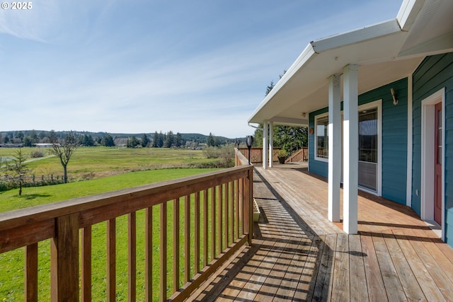 wooden terrace with a rural view and a lawn