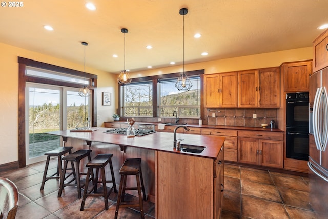 kitchen featuring tasteful backsplash, brown cabinets, a sink, and gas stovetop