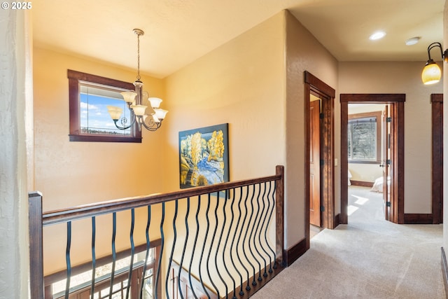 hall featuring carpet floors, a wealth of natural light, baseboards, and an upstairs landing