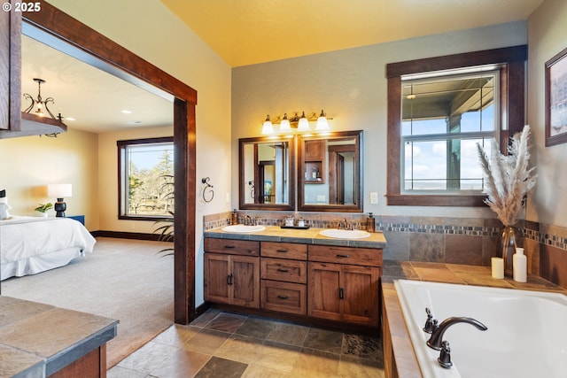 ensuite bathroom featuring double vanity, a sink, a bath, and connected bathroom