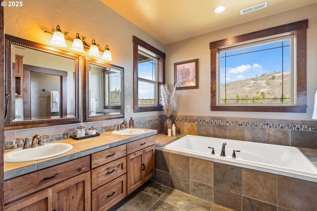 full bath featuring a bath, double vanity, a sink, and visible vents