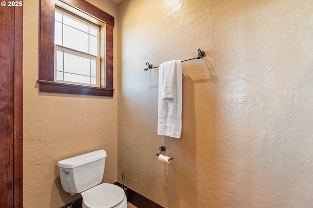 bathroom featuring a textured wall and toilet