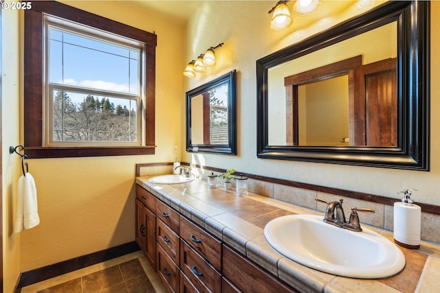 full bath with tile patterned flooring, a sink, baseboards, and double vanity