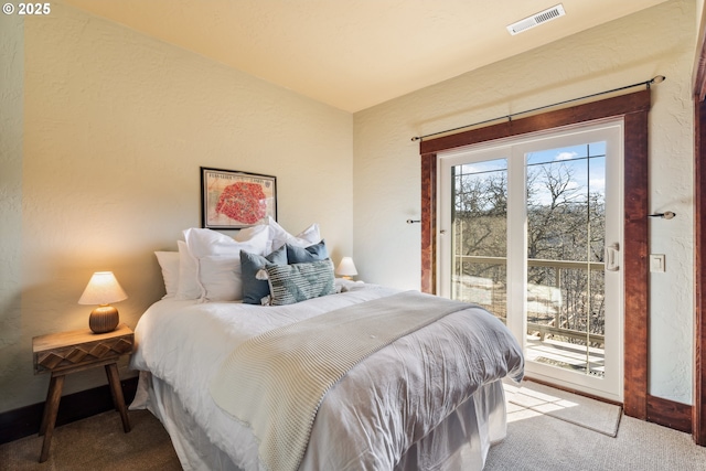 bedroom with a textured wall, carpet flooring, visible vents, and access to exterior