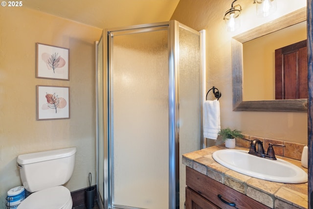 bathroom featuring vanity, a shower stall, and toilet