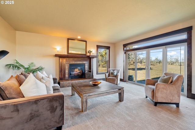 living room featuring light colored carpet, baseboards, a glass covered fireplace, and french doors