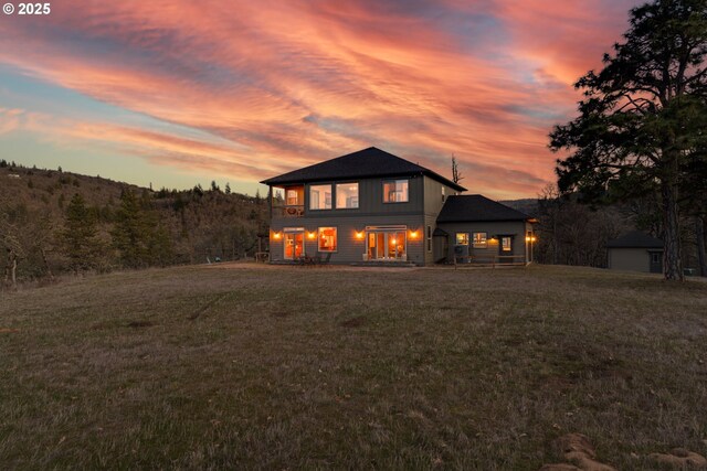 back of house at dusk with a yard