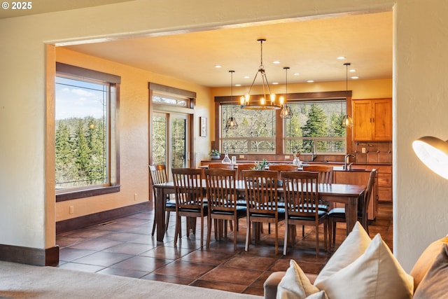 dining space featuring a textured wall, recessed lighting, a notable chandelier, dark tile patterned floors, and baseboards