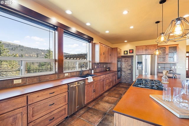 kitchen featuring appliances with stainless steel finishes, hanging light fixtures, a sink, backsplash, and recessed lighting