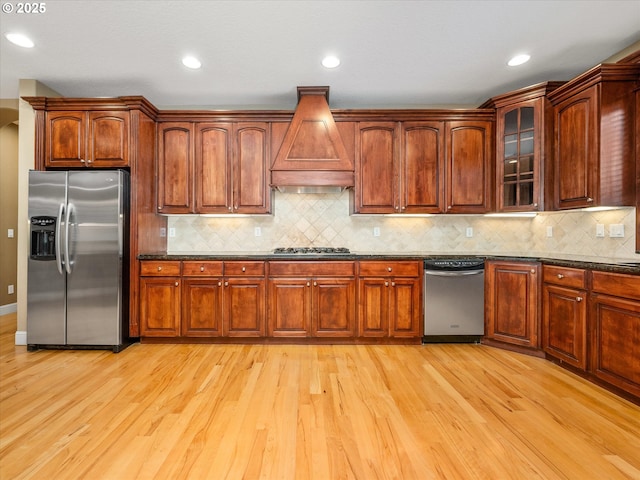 1303 NE 147th Ave, Vancouver, WA 98684 - kitchen with appliances with stainless steel finishes, custom range hood, light wood-type flooring, decorative backsplash, and glass insert cabinets